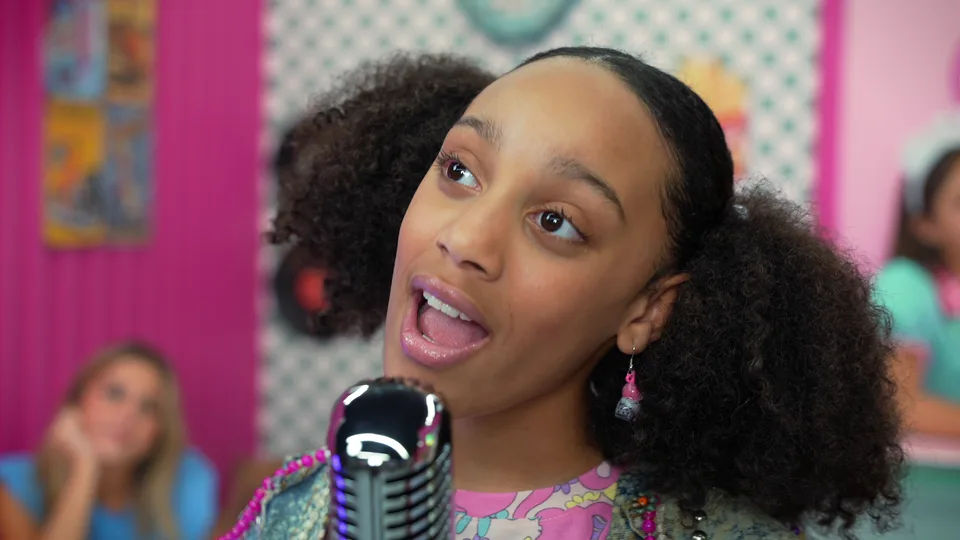 A close-up of the singer looking up as she sings, in a floral outfit