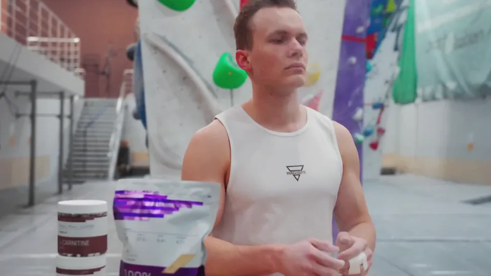 The climber chalking his hands next to the product in a climbing gym