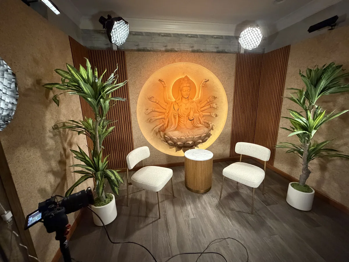 After: the finished studio with acoustic walls, wood slat panels, lights rigged overhead, two chairs and a lit wall relief
